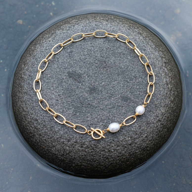 Witte zoetwater parelketting met goud aluminium en barok parels liggend op steen | Gold Paperclip Pearl