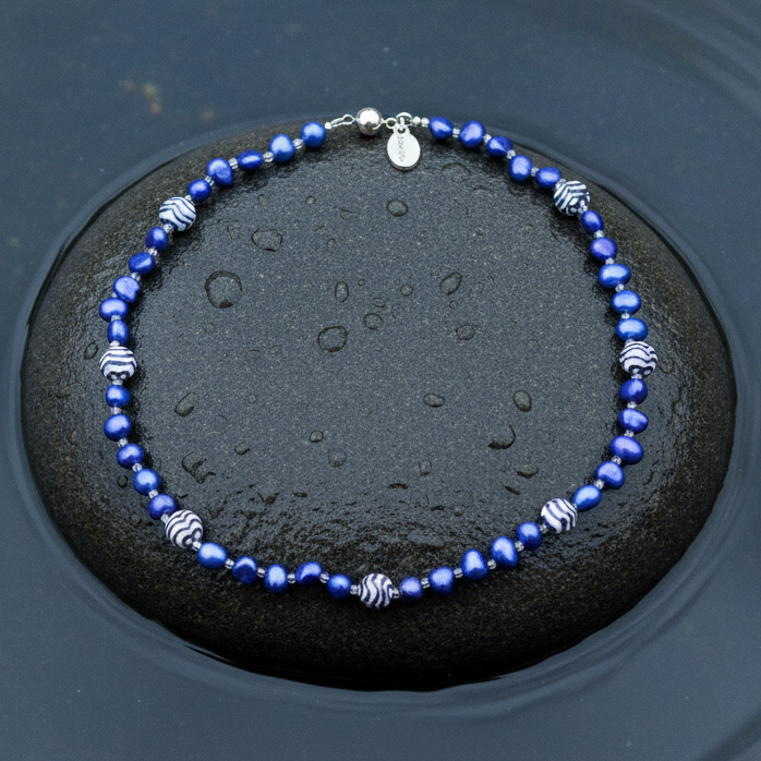 Zoetwater parelketting met blauw parels, kralen met Delfts blauw motief en magneetslotje liggend op steen in water | Hollands Glorie Golfje Blauw