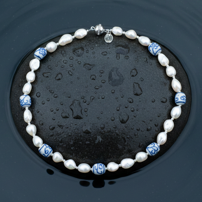 Zoetwater parelketting met witte parels, kralen met Delfts blauw motief en magneetslotje liggend op steen in water | Hollands Glorie Spiral White