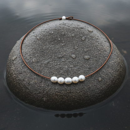 Witte parelketting met 6 parels en echt licht bruin leer liggend op steen in water | Joanne