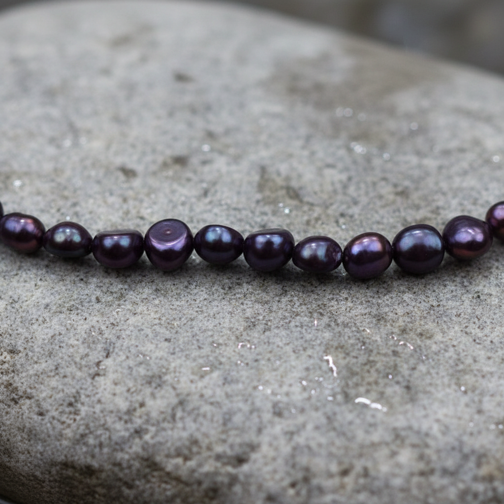 Blauw paarse zoetwater parelketting met gerhodineerd zilveren slotje op steen in water close up | Pealca