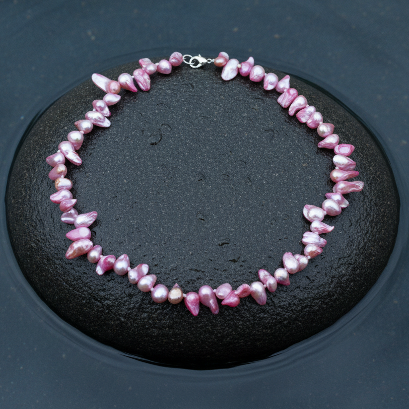 Handgeknoopte zoetwater parelketting met roze parels en sterling zilver (925) liggend op steen in water | Pink Blister