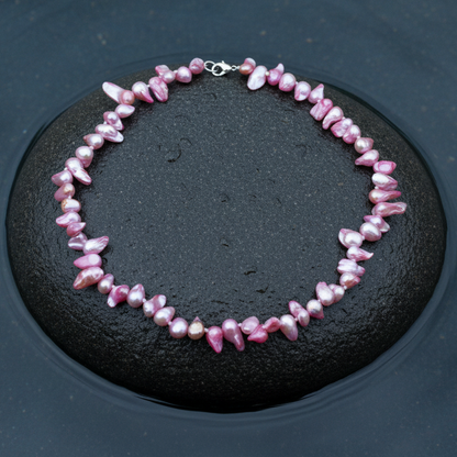 Handgeknoopte zoetwater parelketting met roze parels en sterling zilver (925) liggend op steen in water | Pink Blister