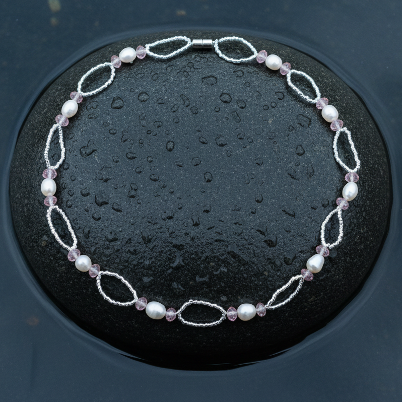 Zoetwater parelketting met witte parels, roze glaskristallen en magneetslotje liggend op steen in water | Rocio