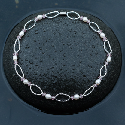 Zoetwater parelketting met witte parels, roze glaskristallen en magneetslotje liggend op steen in water | Rocio