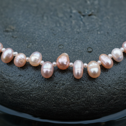 Zoetwater parelketting met zalm roze parels en sterling zilver (925) liggend op steen in water close up | Rozi