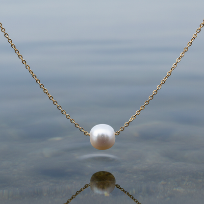 Detail van zoetwater parelketting met witte parel aan goud edelstalen ketting hangt boven water | Single One Pearl Gold