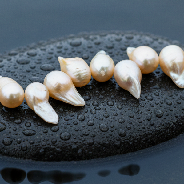 Zoetwater parelketting met zalm kleurige parels en sterling zilver (925) liggend op steen in water close up | Suzet