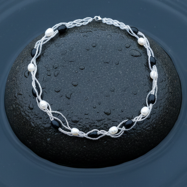 Zoetwater parelketting met witte parels en zwarte glaskralen liggend op steen in water | Twine Pearl Black Glass