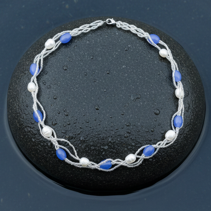 Witte zoetwater parelketting met licht blauwe glaskralen liggend op steen in water | Twine Pearl Heaven Blue