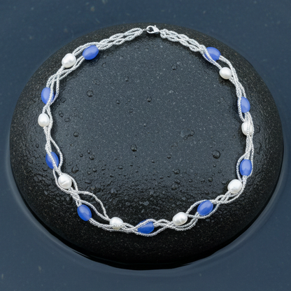Witte zoetwater parelketting met licht blauwe glaskralen liggend op steen in water | Twine Pearl Heaven Blue