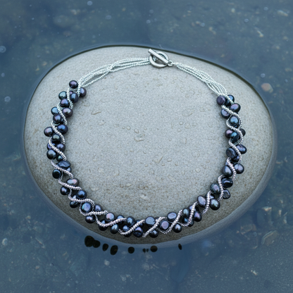 Zoetwater parelketting met blauw zwarte parels liggend op steen in water | Veronica