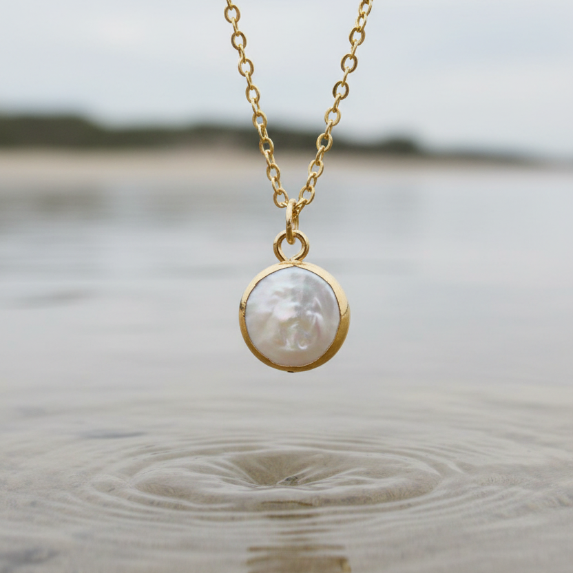 Detail van witte zoetwater parelketting met hanger hangend boven water | White Coin Pearl Gold Small