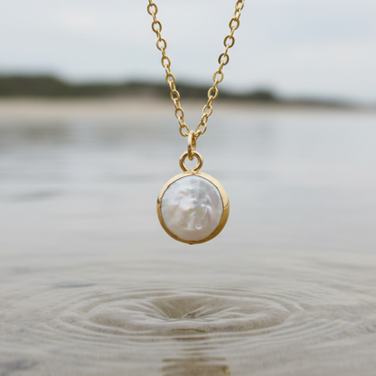 Detail van witte zoetwater parelketting met hanger hangend boven water | White Coin Pearl Gold Small