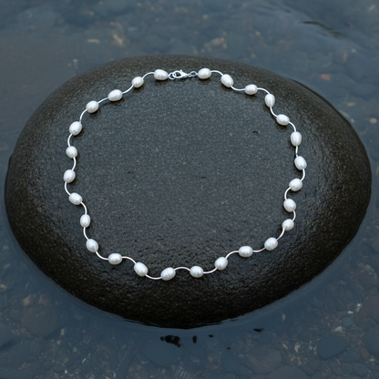 Witte parelketting Wiande liggend op steen in water