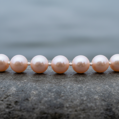Handgeknoopte zoetwater parelketting met zalm kleurige parels en sterling zilver (925) liggend op steen close up | Zalina