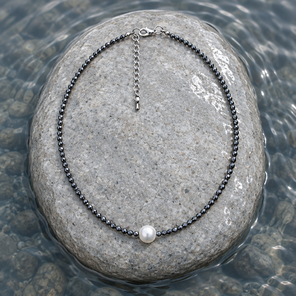 Zoetwater parelketting met witte parel, zwarte edelsteen hematiet en sterling zilver (925) liggend op steen in water | Hematite Pearl W 
