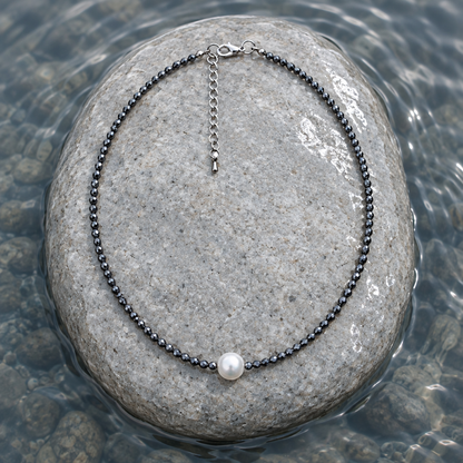 Zoetwater parelketting met witte parel, zwarte edelsteen hematiet en sterling zilver (925) liggend op steen in water | Hematite Pearl W 