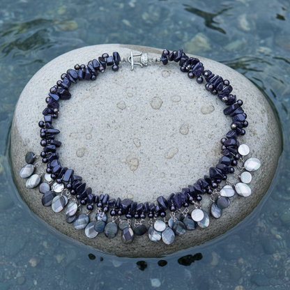Zoetwater parelketting met blauw zwarte parels, donker blauwe edelsteen goudsteen en grijs parelmoer liggend op steen in water  | Glossy Black Drup