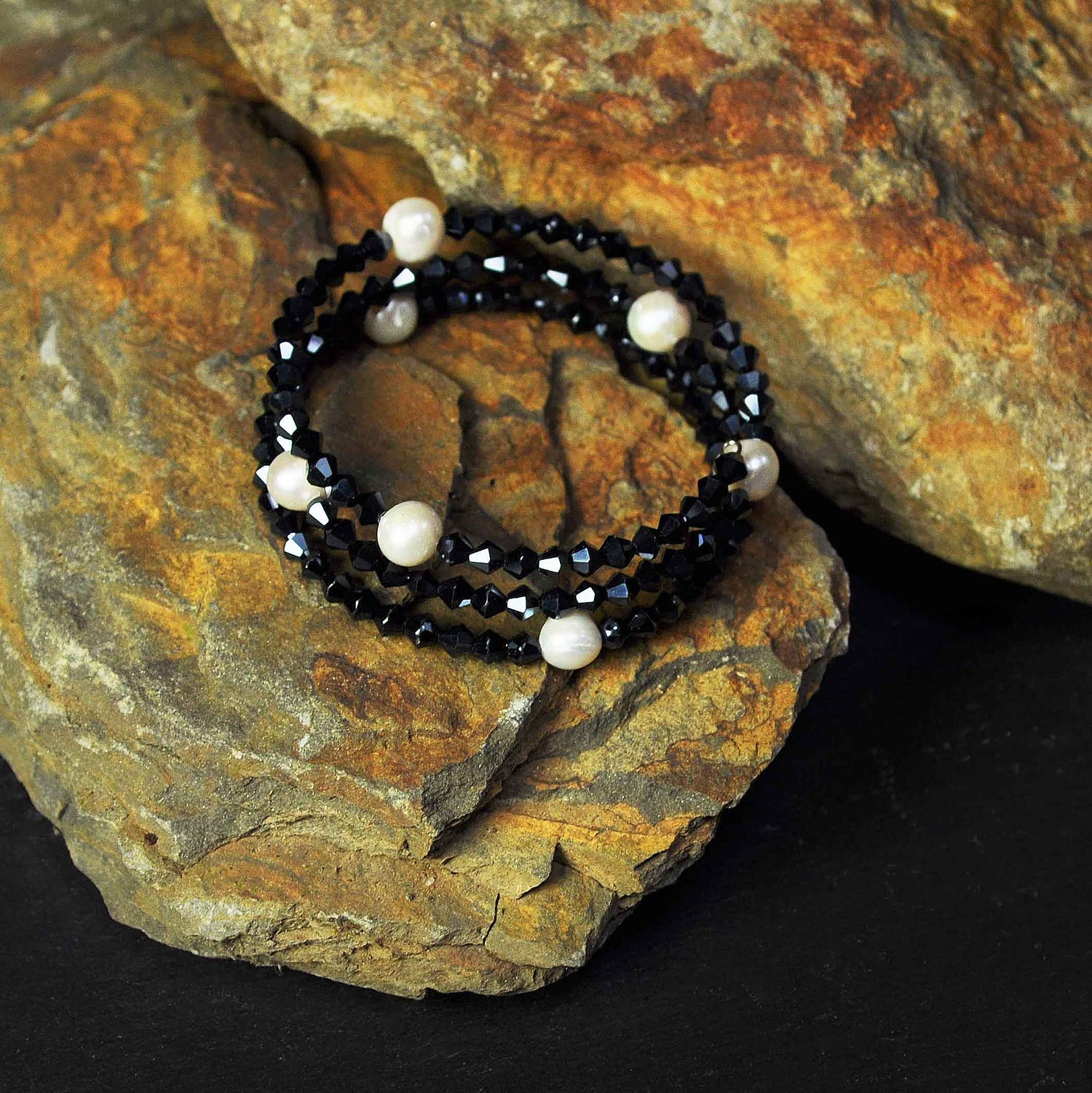 Wit zoetwater parel wikkelarmband met hematiet kleurige stars steentjes liggend op steen | Pearl W Metalic Hematite