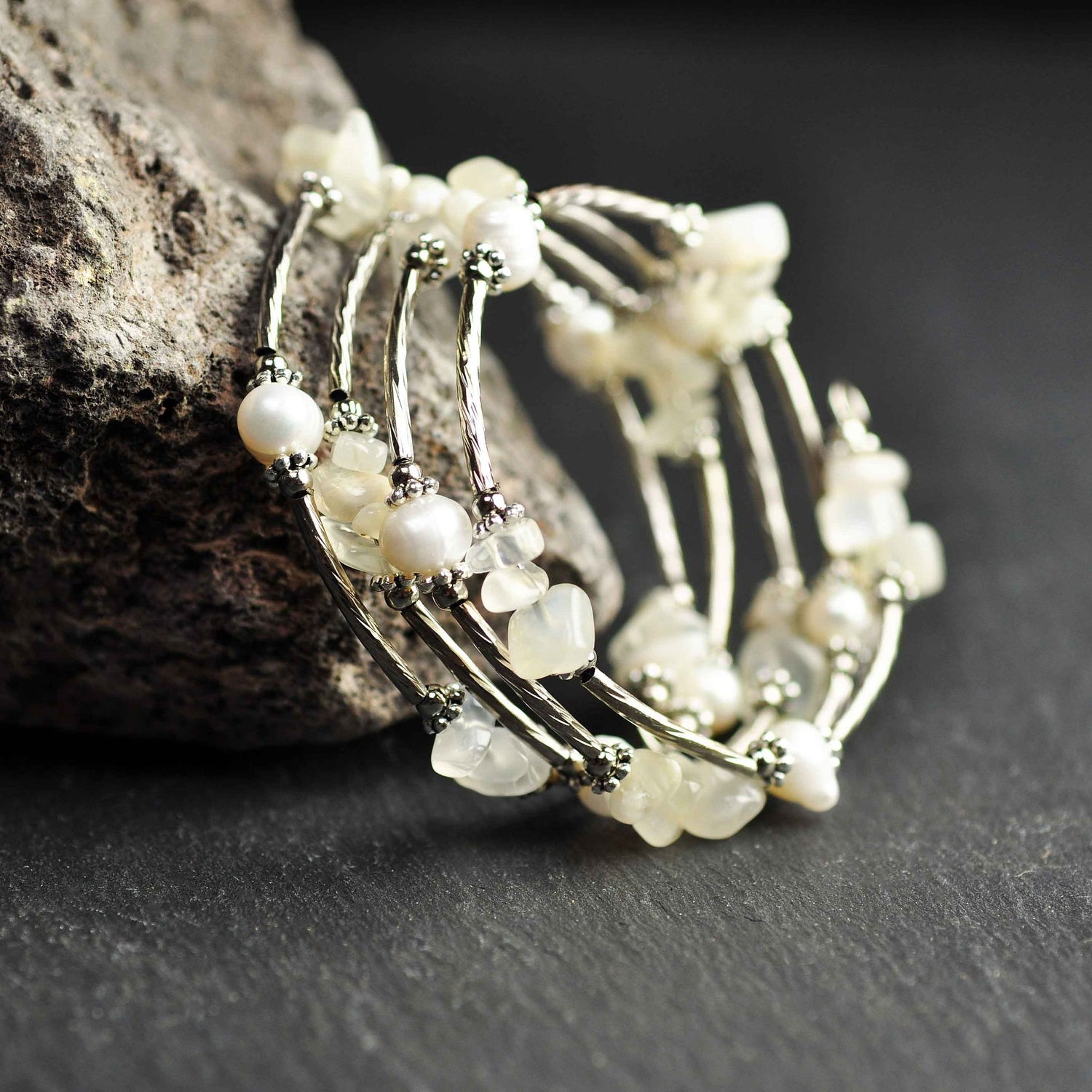 Wit zoetwater parel wikkel armband met edelsteen maansteen en zilver liggend tegen rots | Wrap Pearl Moonstone