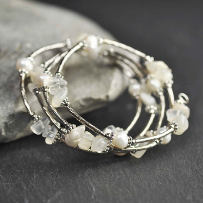 Wit zoetwater parel wikkelarmband met edelsteen maansteen en zilver liggend tegen grijze steen | Wrap Pearl Moonstone