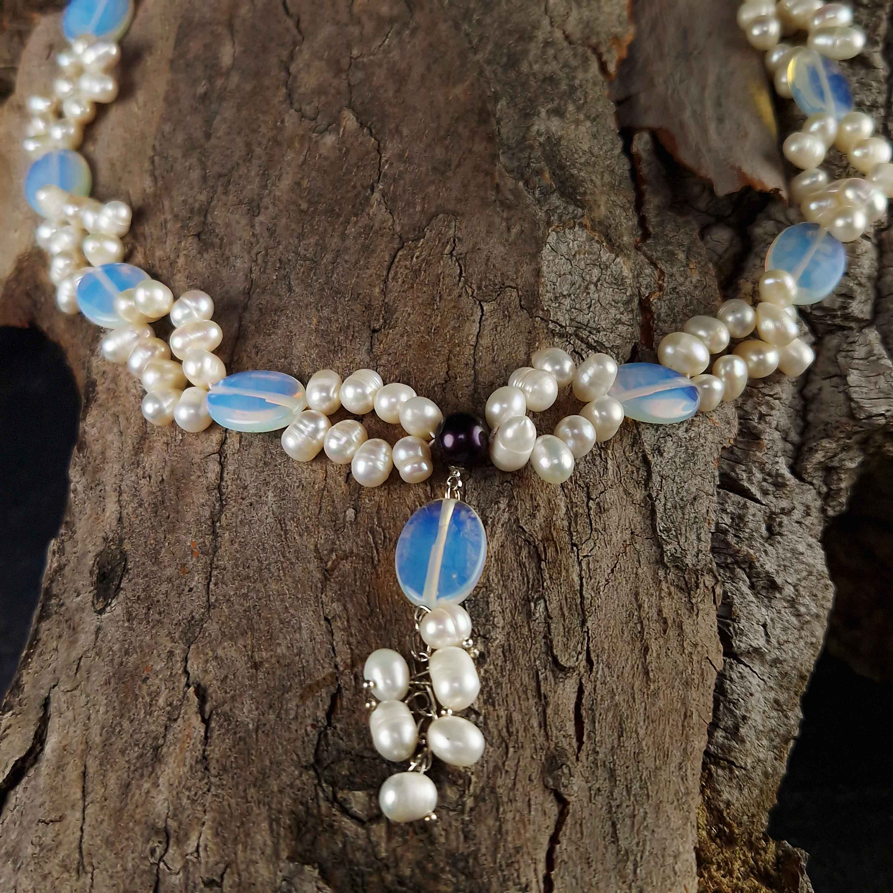 Detail van zoetwater parelketting met witte parels en blauwe edelsteen opaal liggend op hout | Sopal
