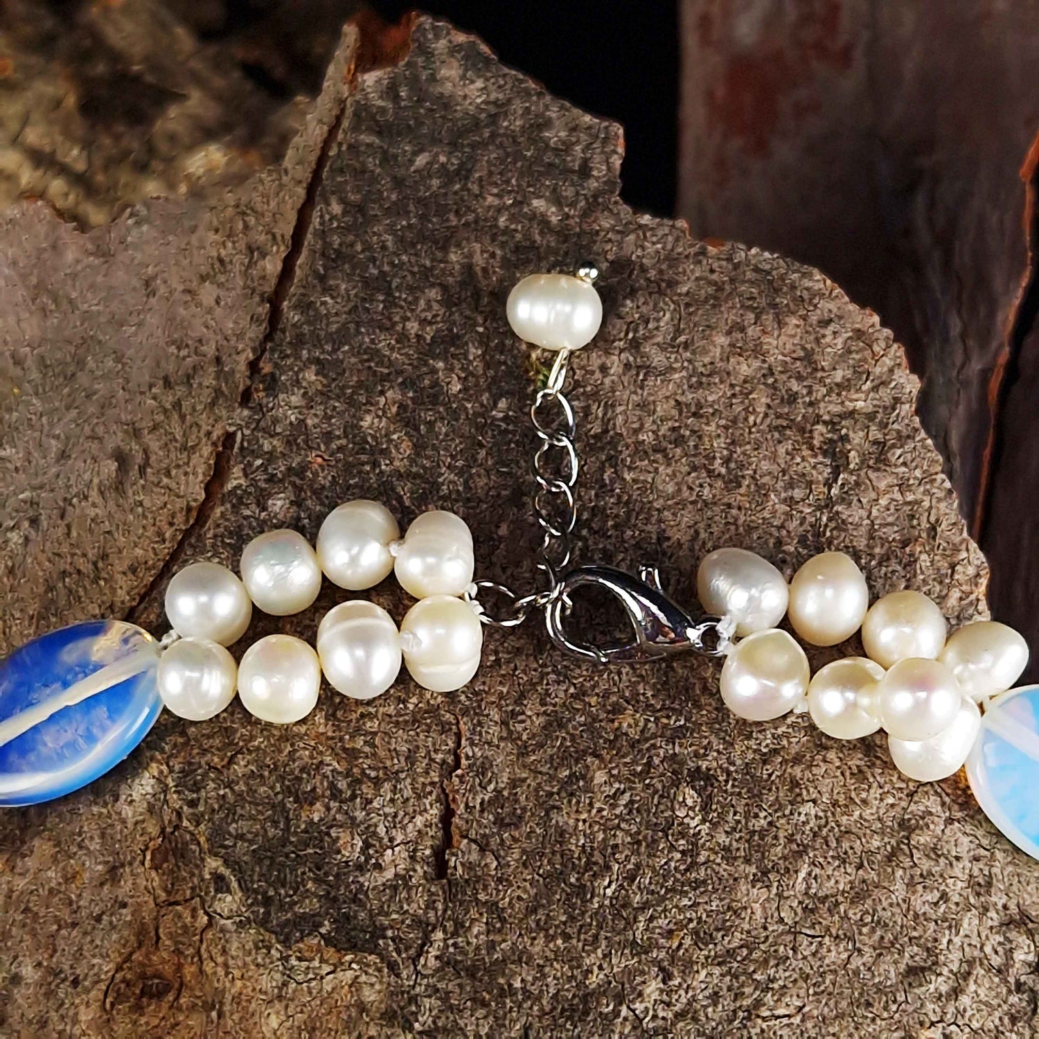 Slotje van zoetwater parelketting met witte parels en blauwe edelsteen opaal liggend op hout | Sopal