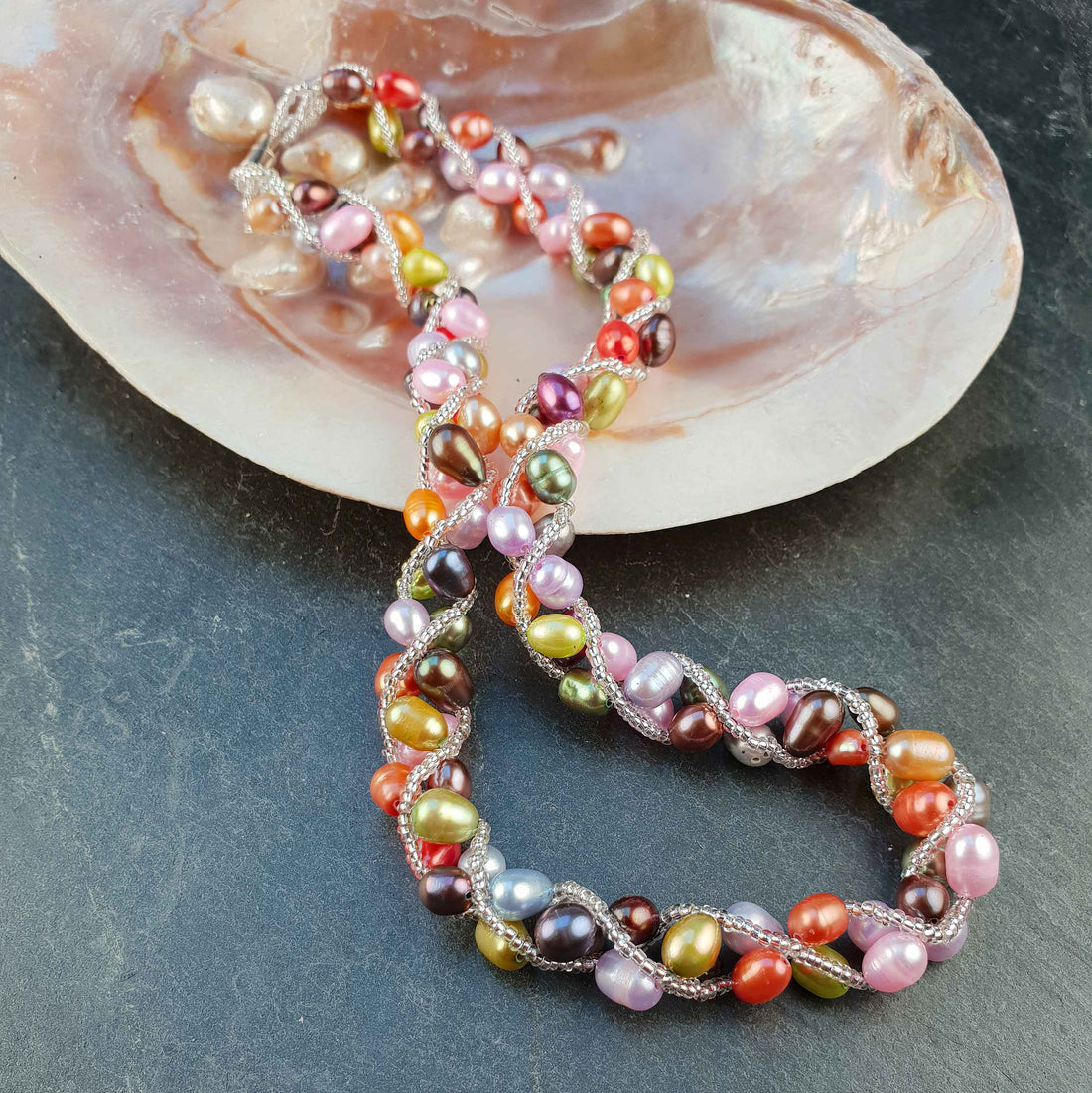 Zoetwater parelketting met vrolijk gekleurde parels en magneetslotje liggend in schelp | Bonica
