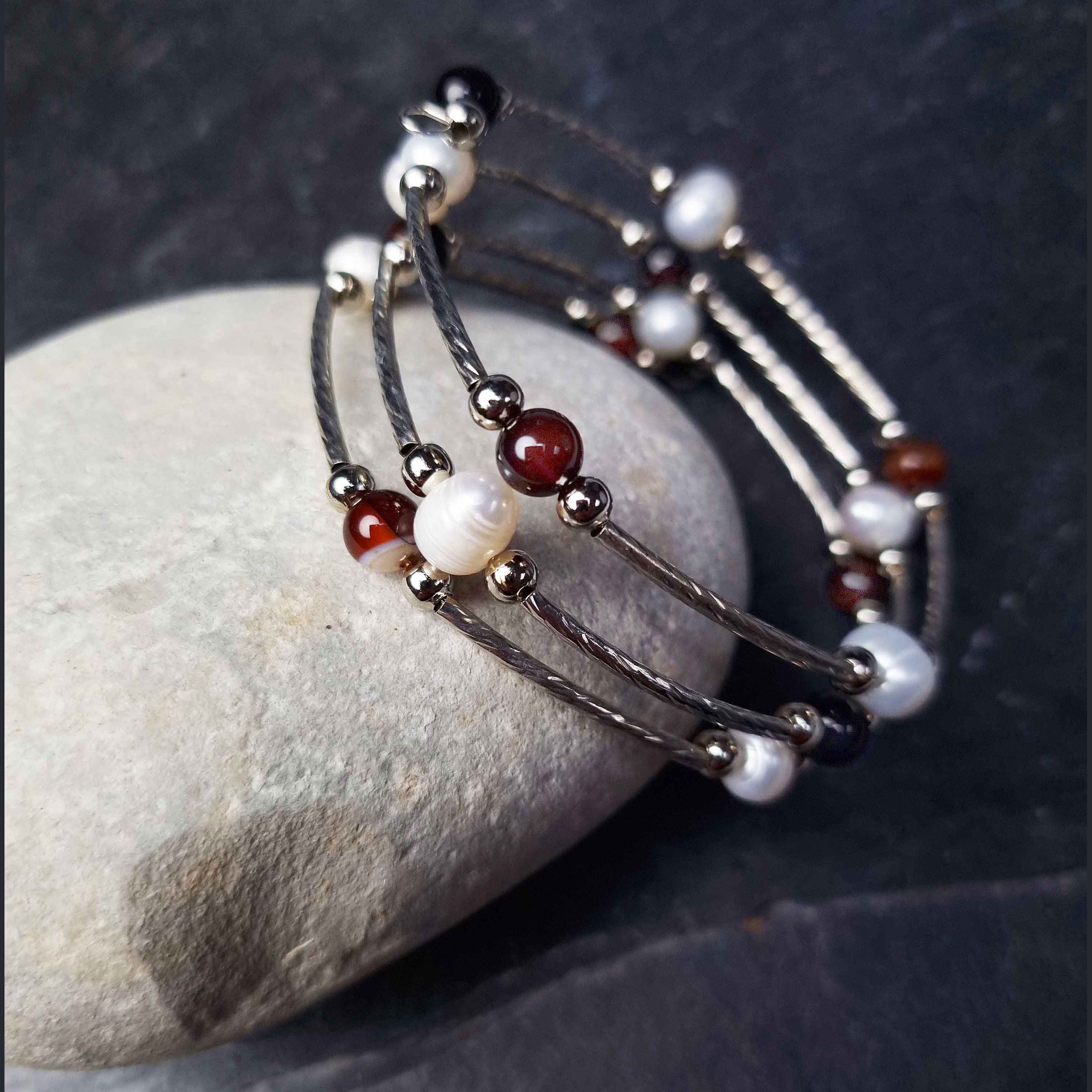 Wit zoetwater parel wikkelarmband met bruine agaat liggend tegen witte kei | Wrap Pearl Brown Striped Agate