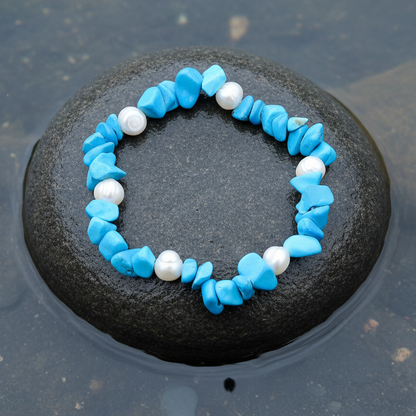 Wit zoetwater parel armband met blauwe edelstenen turkoois, elastisch liggend op steen in water | Pearl Turquoise Chip