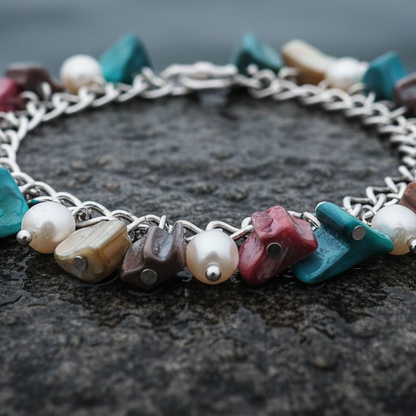 Zoetwater parel bedelarmband met witte parels en gekleurd parelmoer liggend op steen close up | Pearl Color Shell Chip