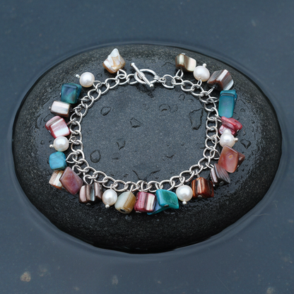Zoetwater parel bedelarmband met witte parels en gekleurd parelmoer liggend op steen in water | Pearl Color Shell Chip
