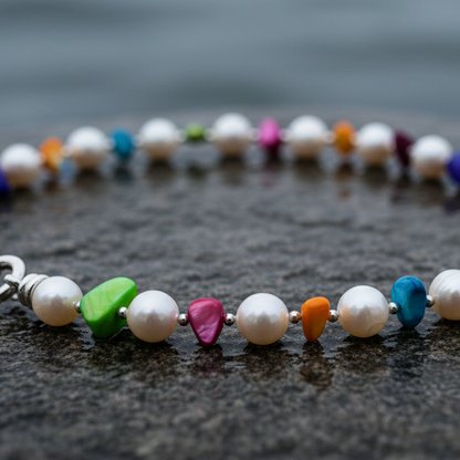 Zoetwater parelketting met witte parels en gekleurd parelmoer liggend op steen close up | Big Bold Happy 