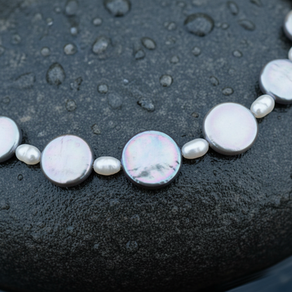 Zoetwater parelketting met witte parels, grijs parelmoer en zilver edelstaal  liggend op steen in water close up | set Pearl Grey Shell R