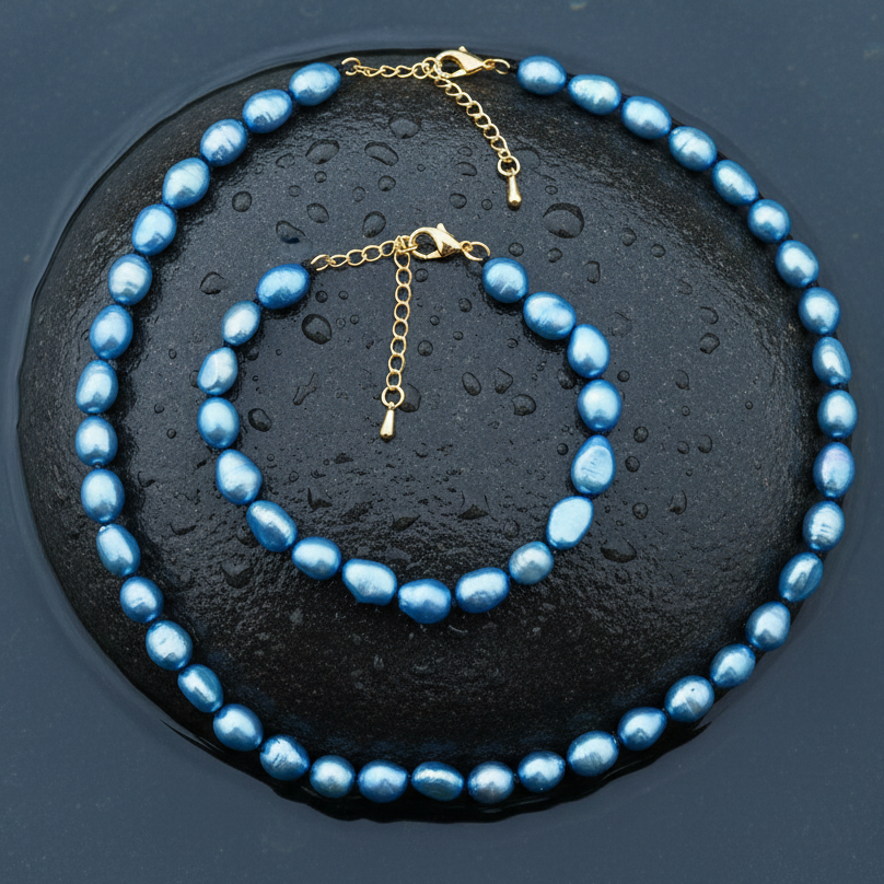 Blauw zoetwaterparel ketting en armband met goud edelstalen slotje is volledig handgeknoopt met barok parels  en ligt op een steen in water | Blair