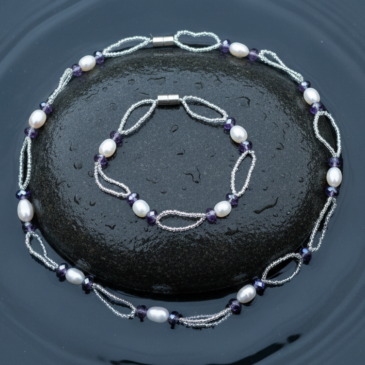 Zoetwater parel set bestaande uit een parelketting en parel armband met witte parels, paars glaskristallen en magneetslot liggend op steen in water | set Pacio