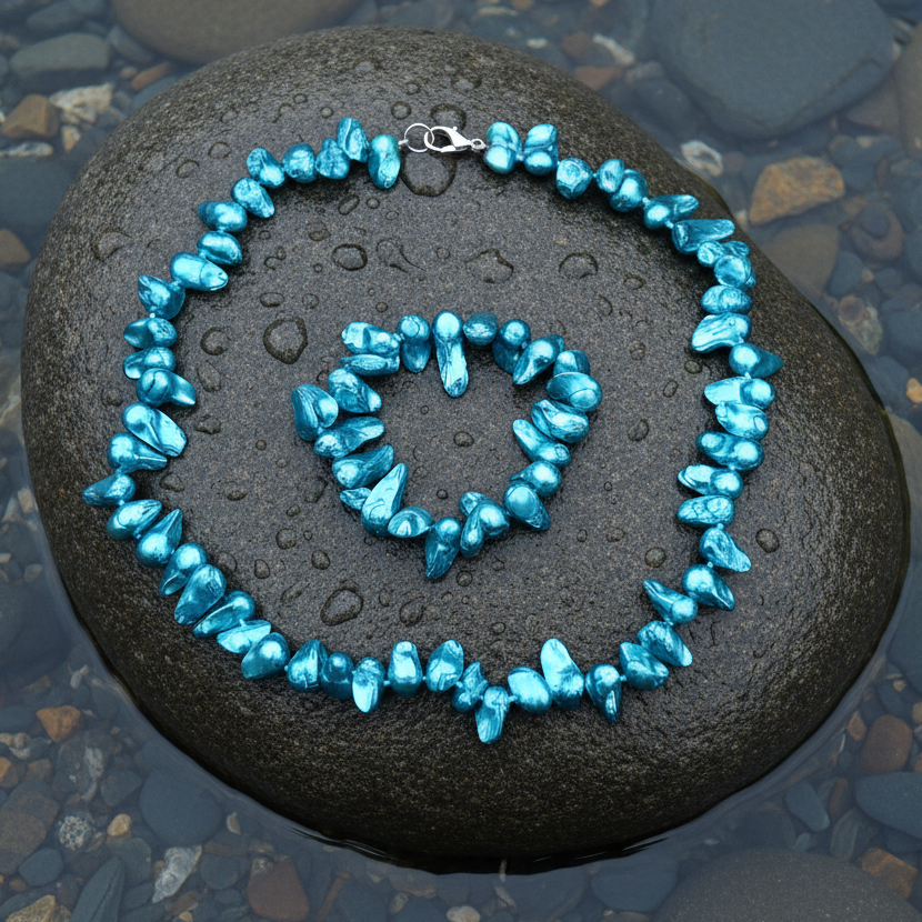 Zoetwater parel set bestaande uit een parelketting en parel armband met aqua blauwe parels en sterling zilver (925) liggend op steen in water | set Pearl Blister Aqua Blue (KA)
