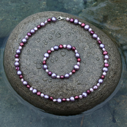 Lila en bordeaux parel set met ketting en armband op natte grijze steen