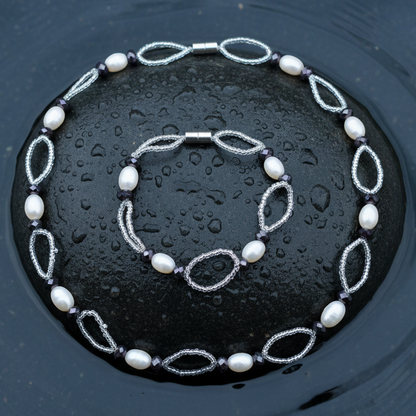 Zoetwater parel set bestaande uit parelketting en parel armband met witte parels, zwarte glaskristallen en magneetslot liggend op steen in water | set Zwicio