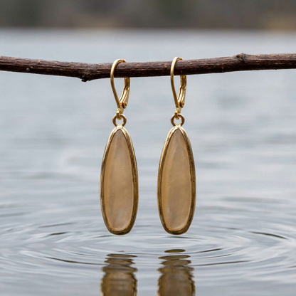 Beige parelmoeren oorbellen met goud kleurig edelstaal hangend aan takje boven water | Oblong Drop Beige