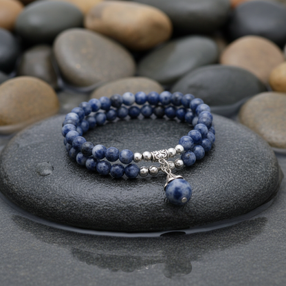 Blue Spot Ball armband variant op grijze natte steen bij oever