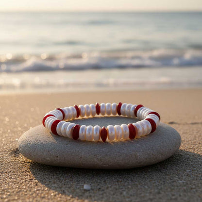 Parel armband met witte coin parels en rood koraal liggend op kei op strand | Elastisch | Coral Coin Pearl