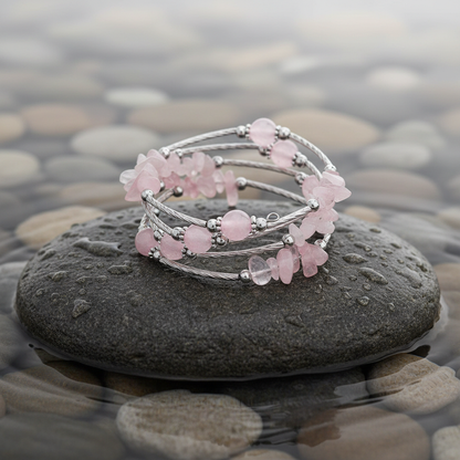 Four Loops Wrap Rose Quartz edelstenen wikkelarmband close-up op grijze natte steen bij oever