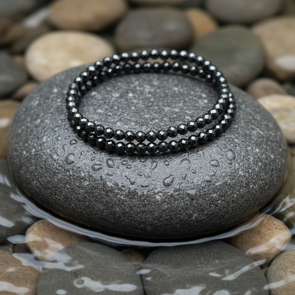 Hematite Wrap Sparkle edelstenen wikkelarmband close-up op grijze natte steen bij oever