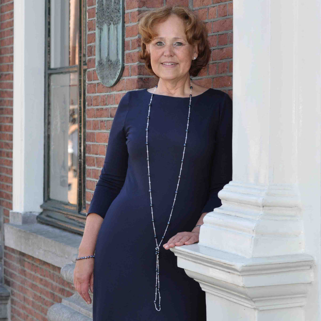 Lange zoetwater parelketting met blauw zwarte parels op model tegen muur | Black Pearl Sweater