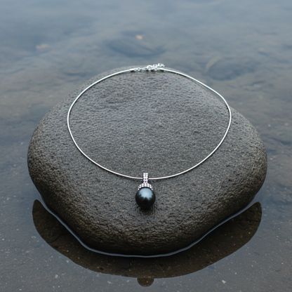 Mother of pearl parelketting met zwart groene parel en stras steentjes liggend op steen | Balanie