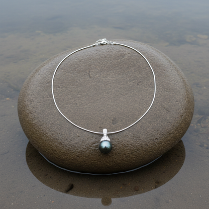 Mother of pearl parelketting met zwart groene parel en stras steentjes liggend op steen | Blizanie