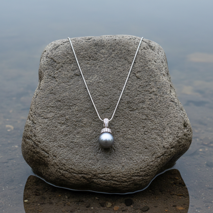 Mother of pearl parelketting met grijze parel en stras steentjes liggend op steen | Glanie