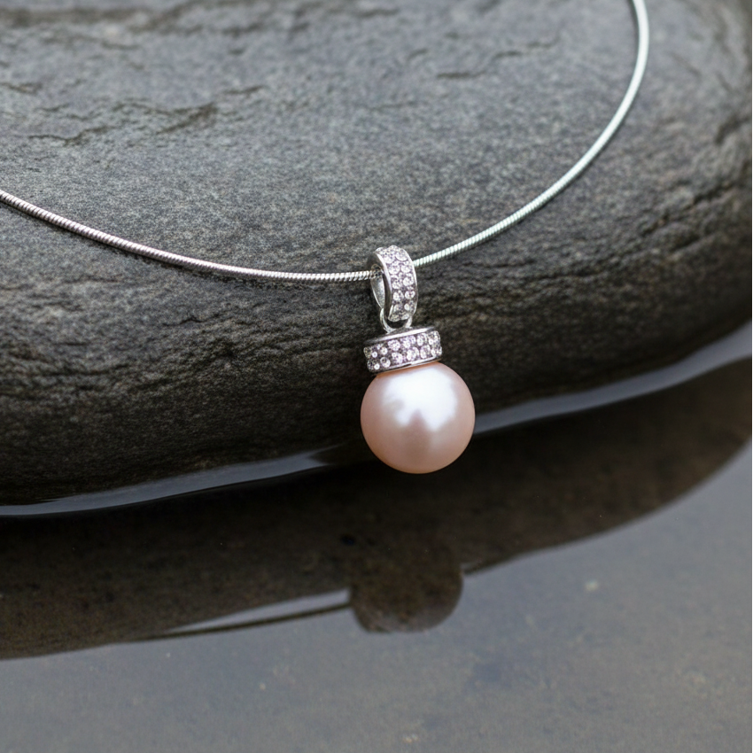 other of pearl parelketting met zalm kleurige parel en stras steentjes close up liggend op steen | Zalamie